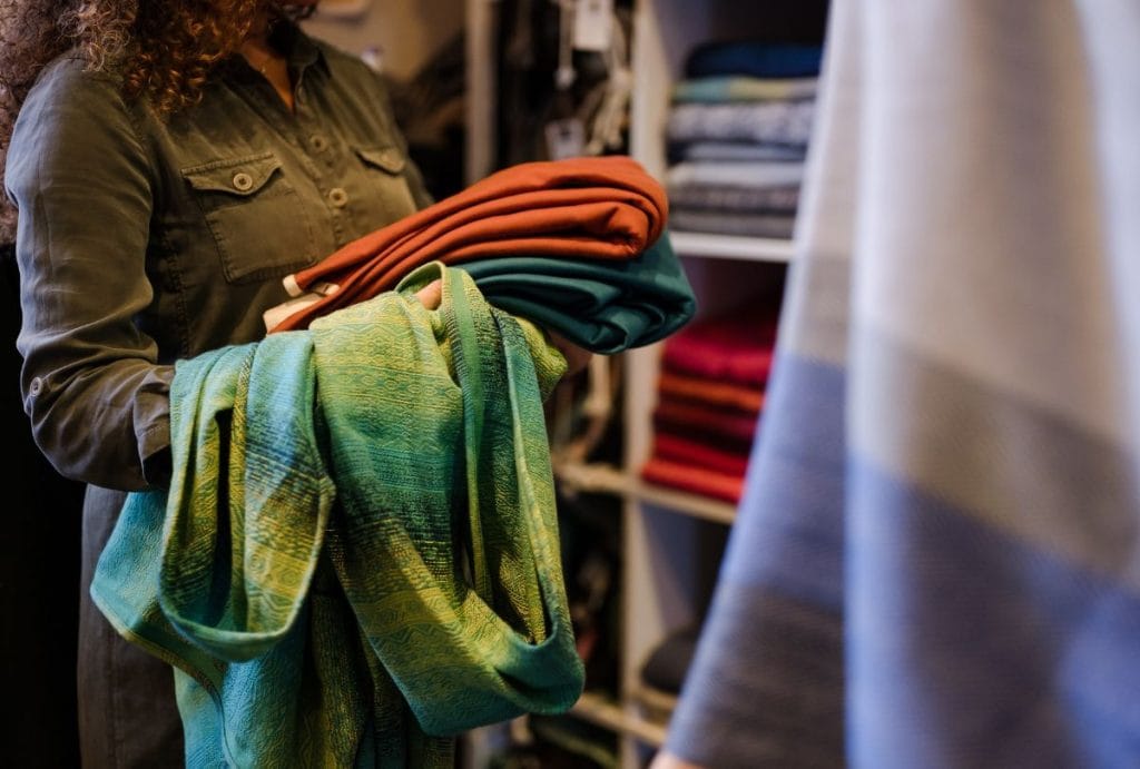 A person carries an armful of didymos baby wraps that meet the baby sling standard